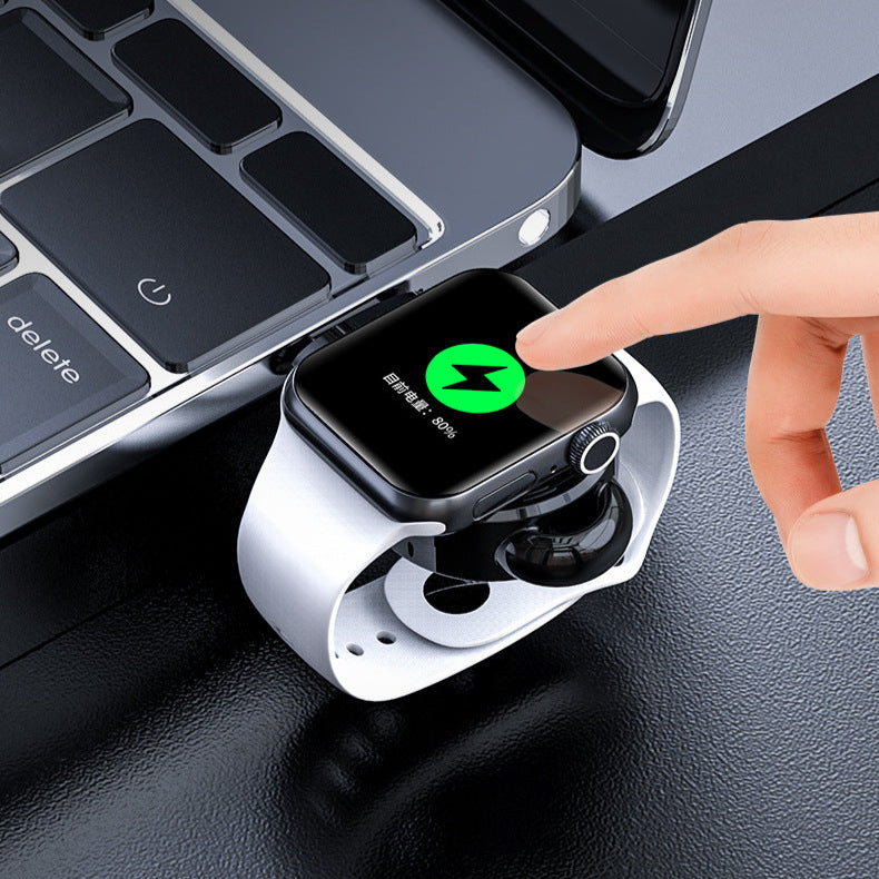 Smartwatch being charged on a stand with a laptop in the background
